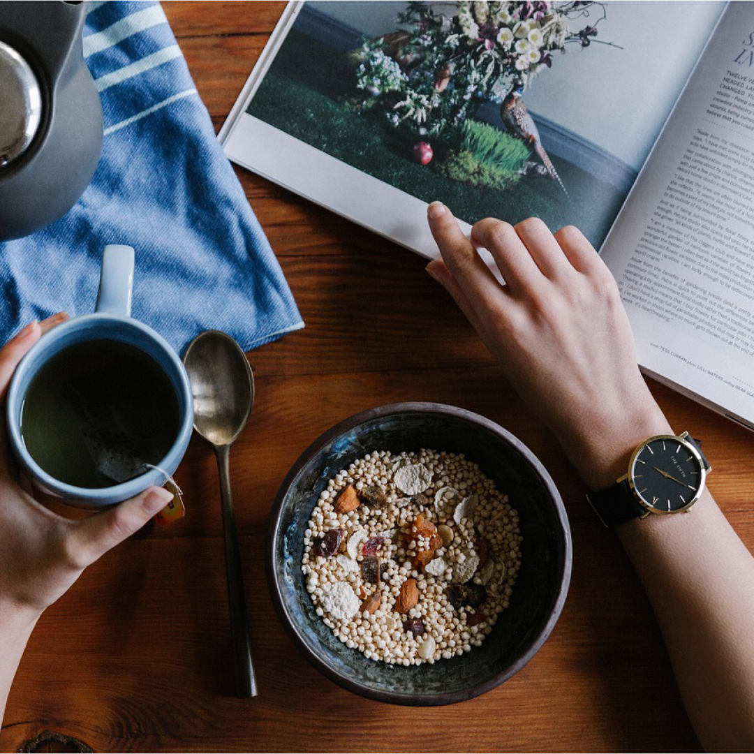 Foto på kaffekopp, kaffetermos, frukostskål med händer som bläddrar i en tidning